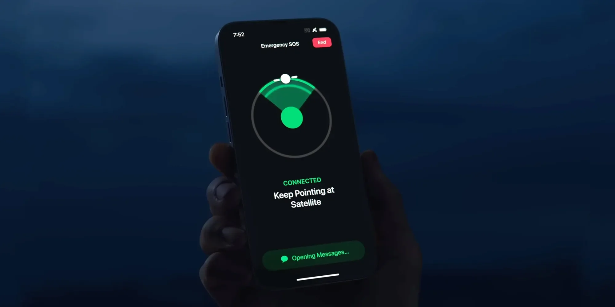 Mano sosteniendo un iPhone en un entorno nocturno con la interfaz de 'Emergencia SOS' abierta, mostrando un radar verde que guía para mantener la conexión satelital activa.