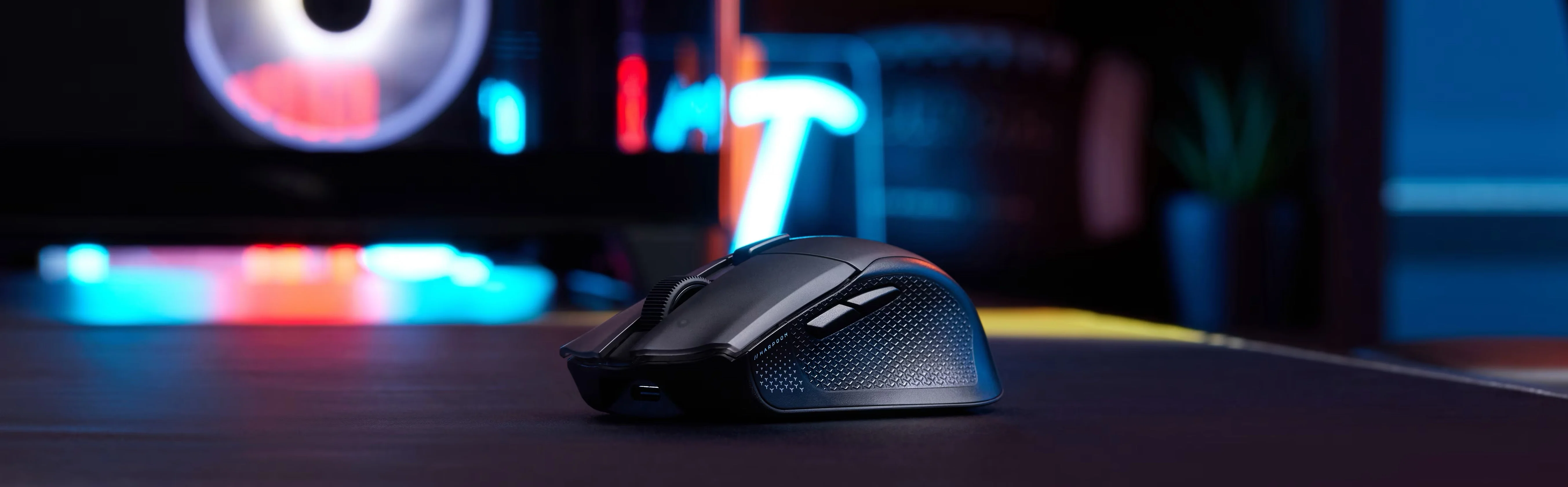 El mouse Harpoon v2 Wireless de perfil sobre un escritorio con luces de neón de fondo
