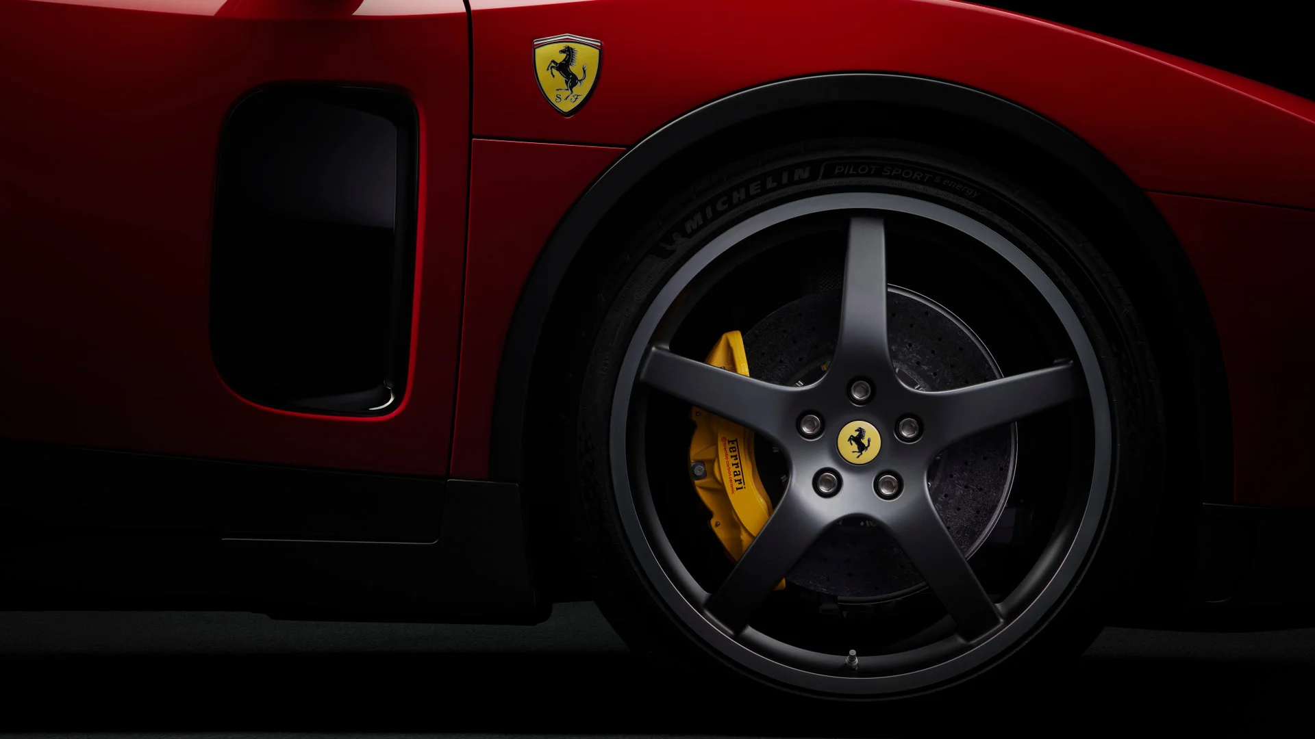 Close-up of the Ferrari Luce's front wheel with matte black five-spoke wheel, Michelin Pilot Sport S energy tire, and yellow brake caliper with Ferrari inscription