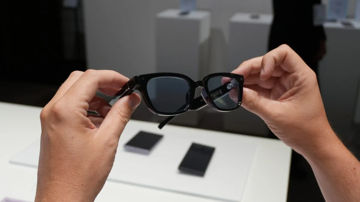 Dos manos sostienen las gafas inteligentes de Samsung mostrando la cámara integrada en la patilla