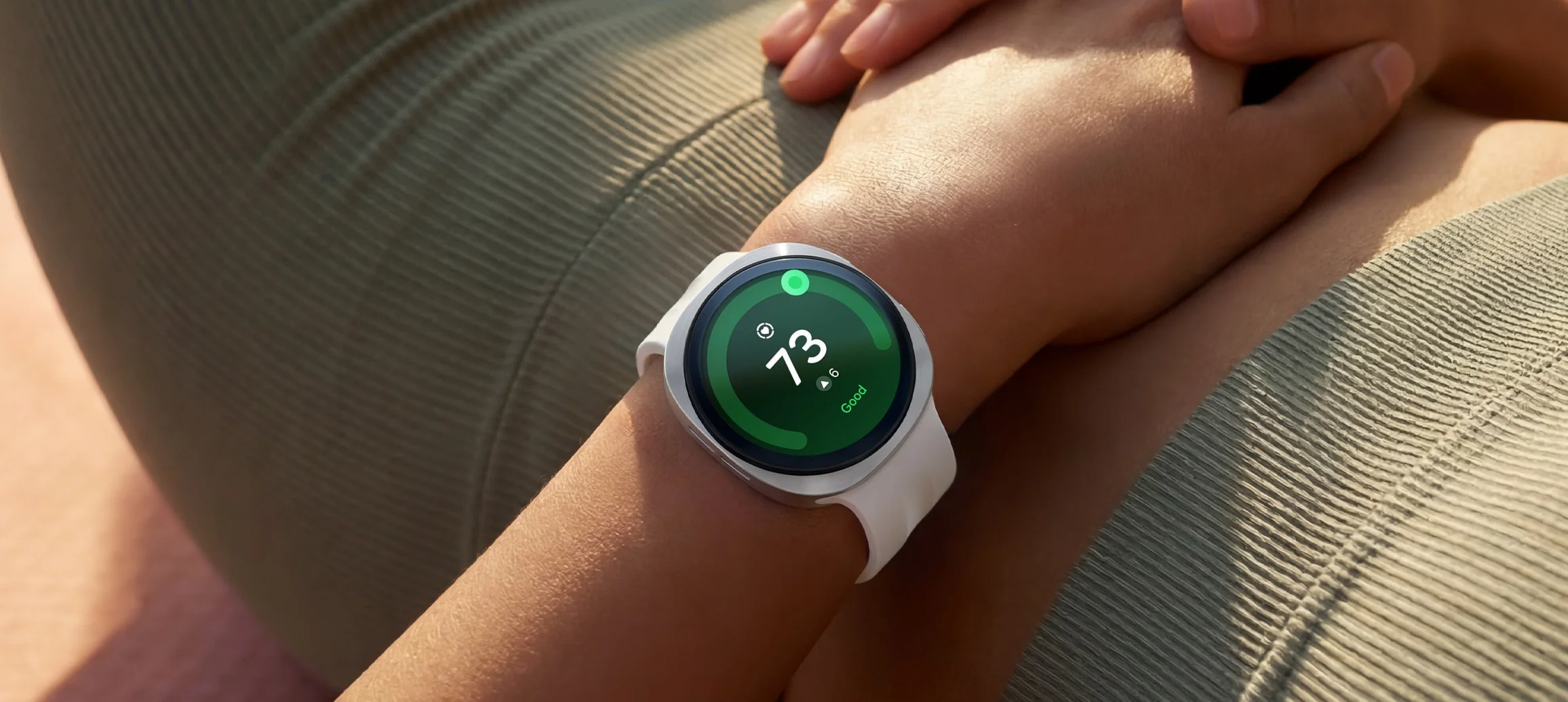 El Galaxy Watch 9 en la muñeca mostrando una puntuación de 73 sobre fondo verde con la etiqueta Good
