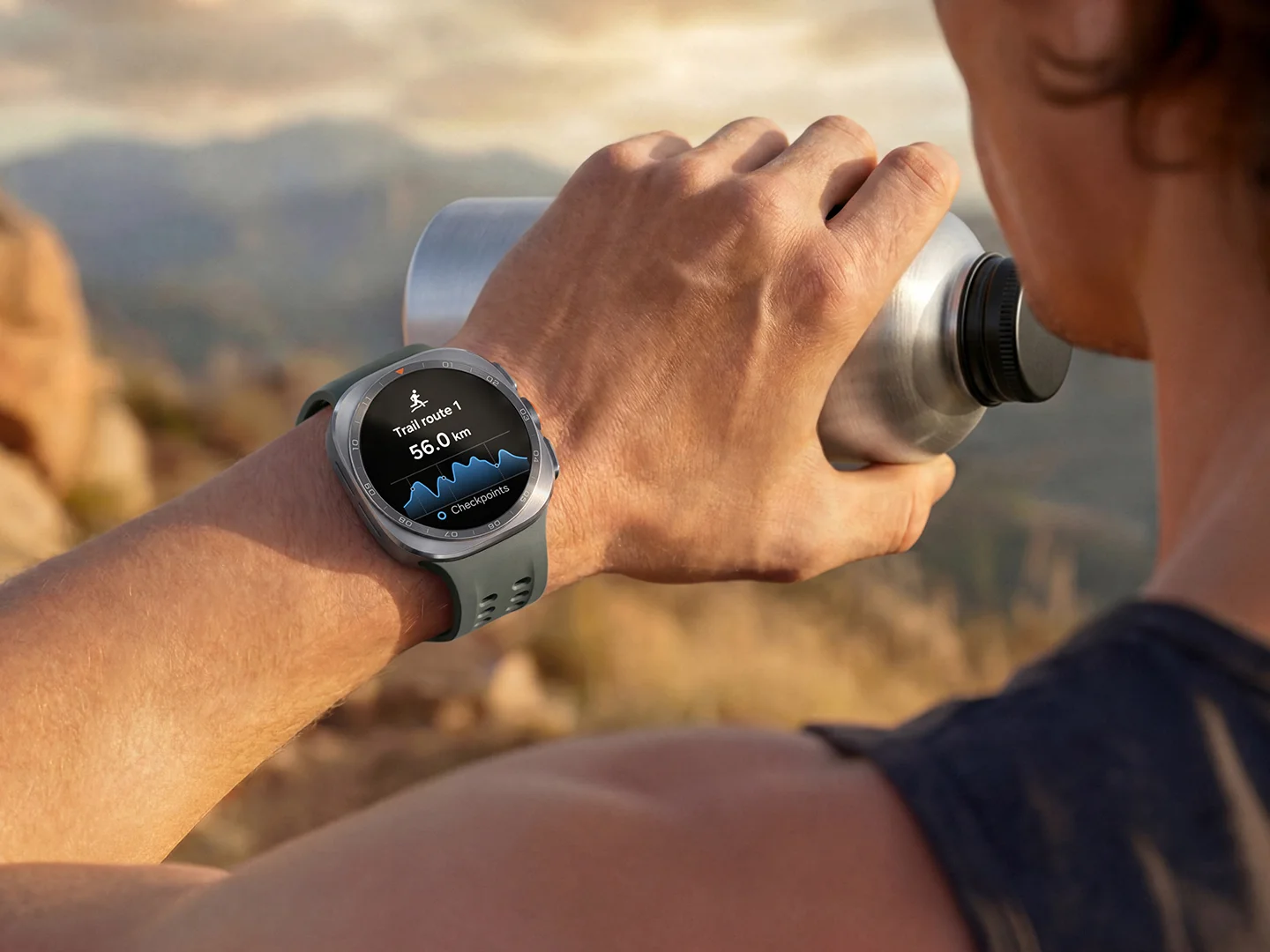 Un corredor bebe agua mientras el Galaxy Watch Ultra 2 muestra una ruta de trail de 56 kilómetros con su perfil de altimetría