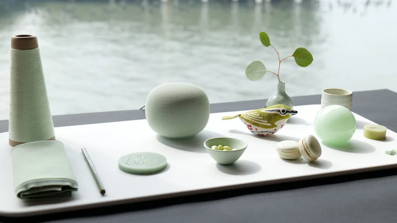 Google Home Speaker Jade en una mesa decorada con un cono de hilo, macarons y un adorno de pájaro