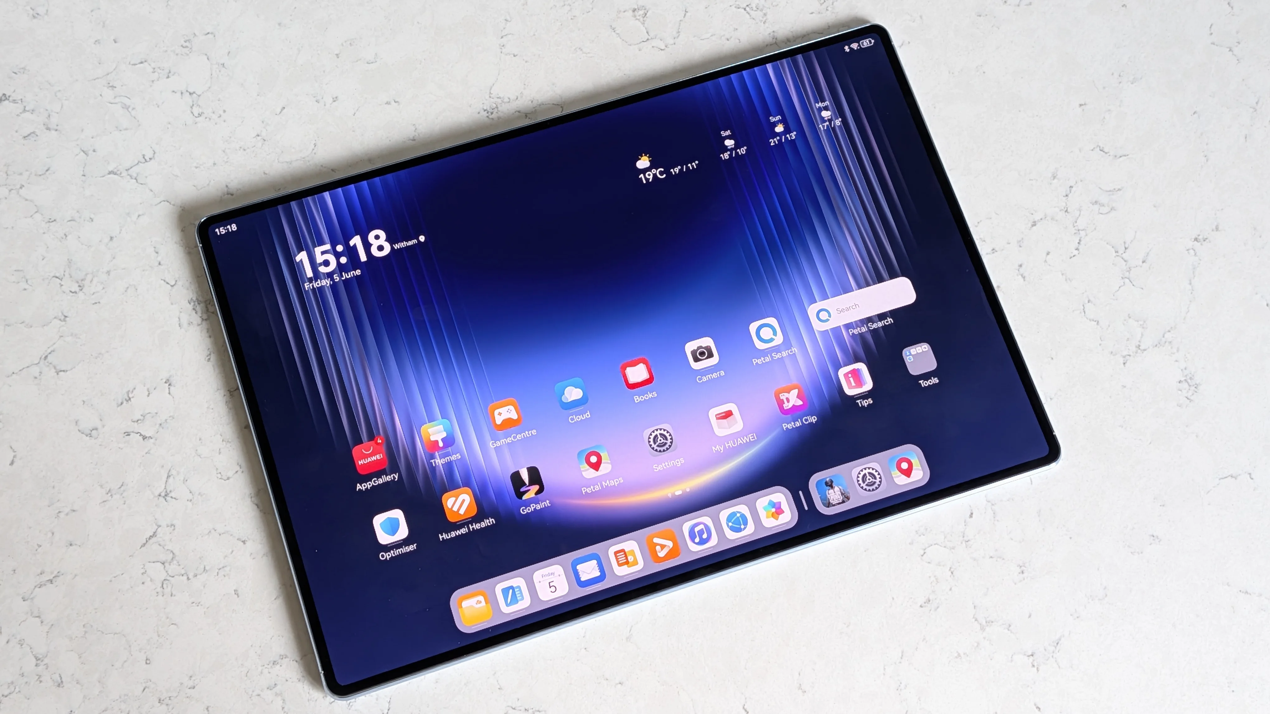 La Huawei MatePad Pro Max apoyada sobre una superficie de mármol con la pantalla de inicio de HarmonyOS.
