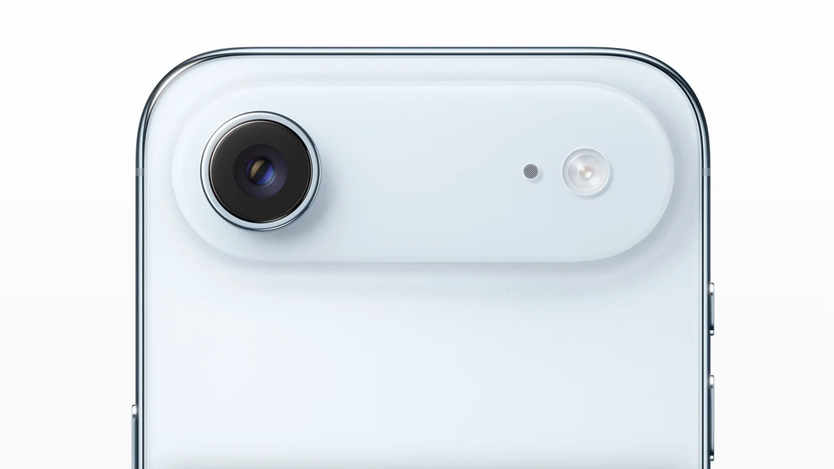 Detail of the upper rear section of a light ice blue iPhone. It highlights a redesigned raised horizontal pill-shaped camera module containing a single large main lens and the flash on one side.