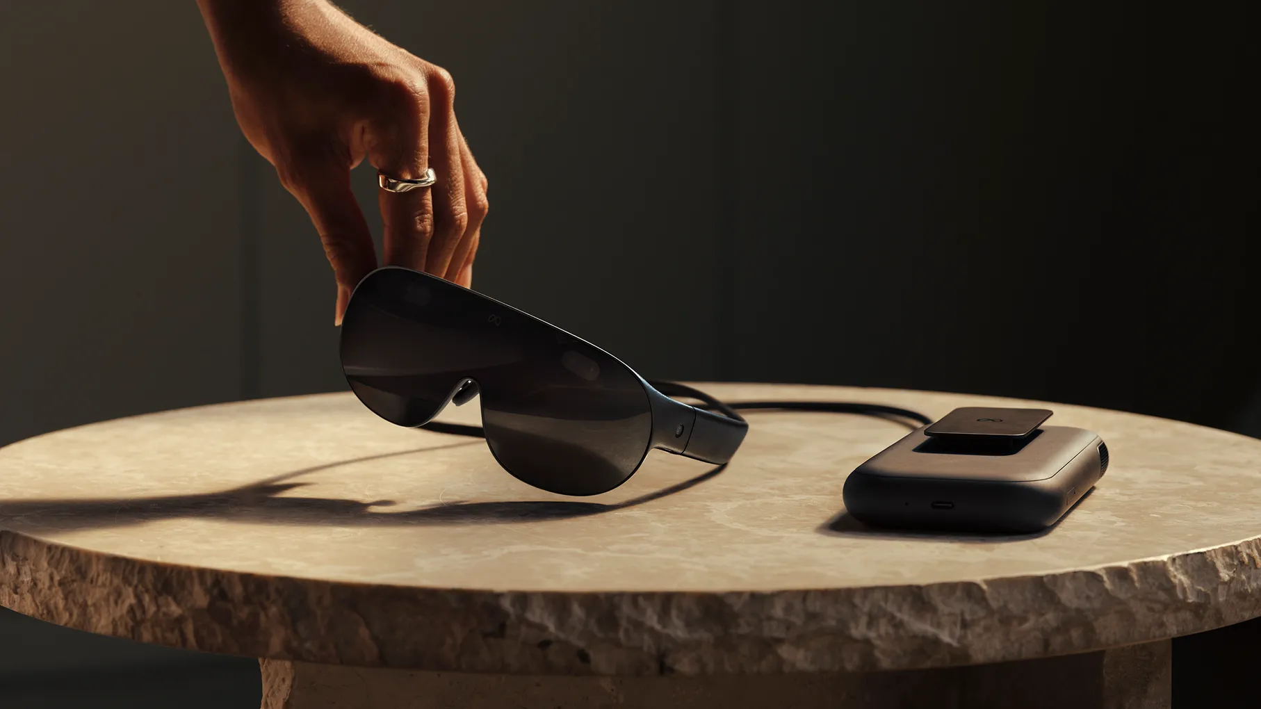 Hand lifting the Meta VR Glasses while the puck remains on a table