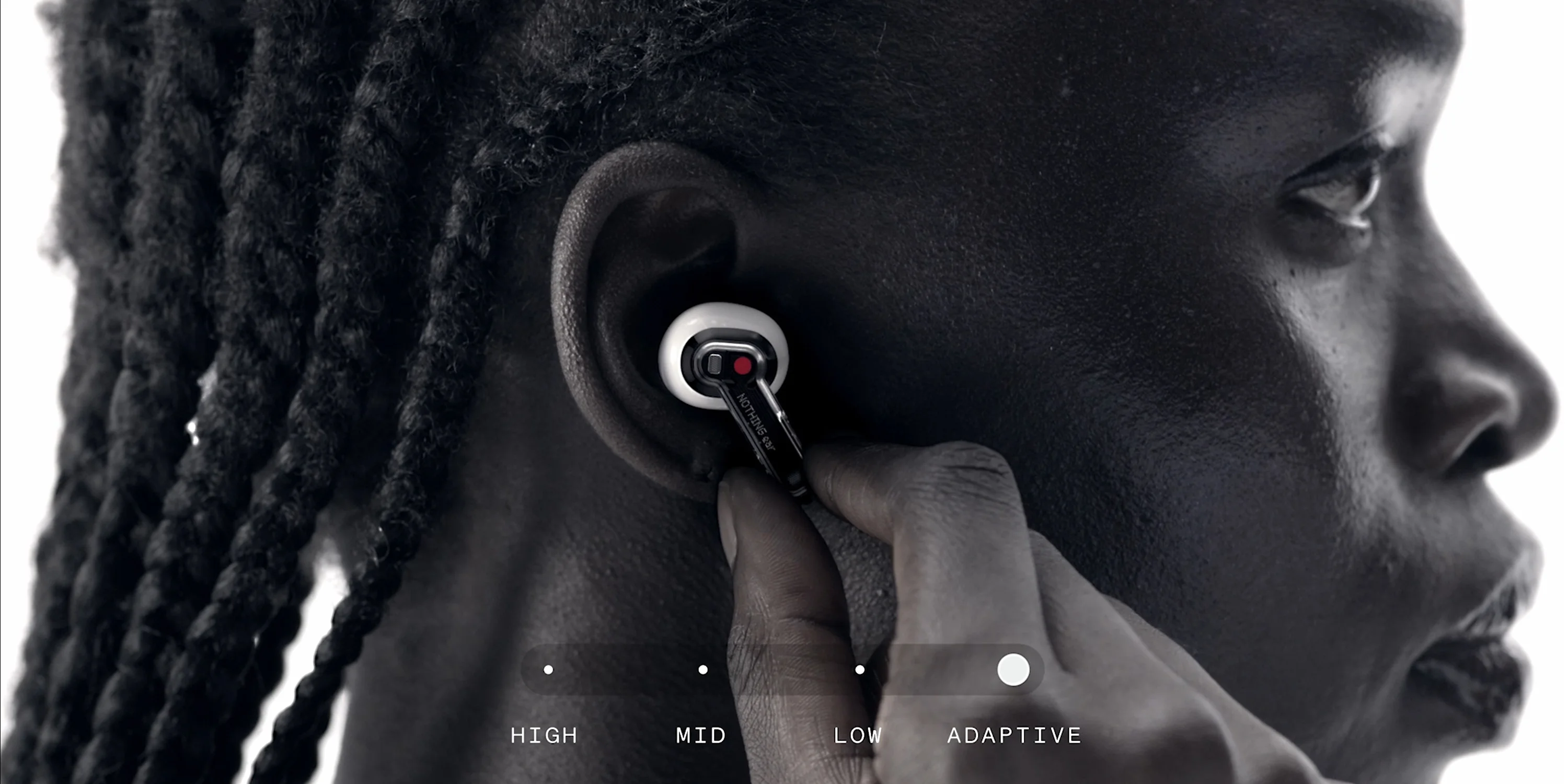 Primer plano en blanco y negro de una oreja con el auricular puesto y el selector de niveles de cancelación de ruido