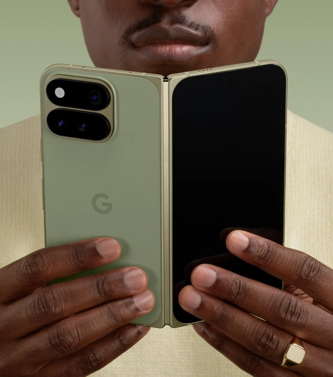 Una persona sostiene el Pixel 11 Pro Fold abierto en color Olive mostrando el dorso y la pantalla interna