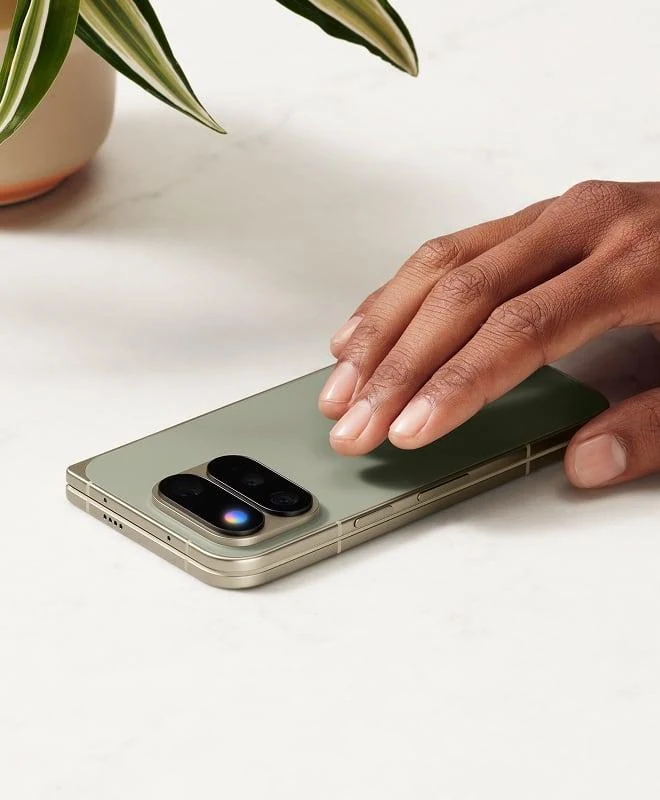 El Pixel 11 Pro Fold en Olive plegado sobre una mesa de mármol junto a una planta
