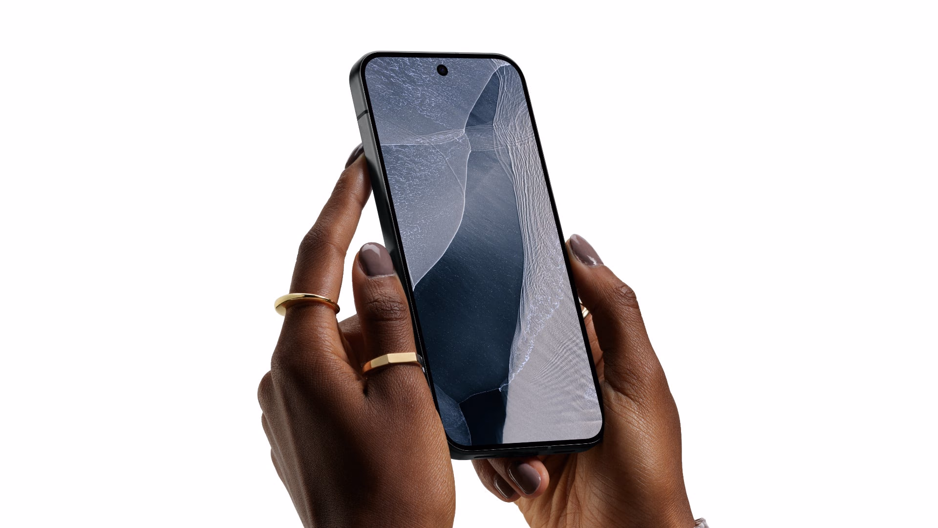 Dos manos sostienen el Pixel 11 Pro en Obsidian mostrando la pantalla encendida con un fondo de olas