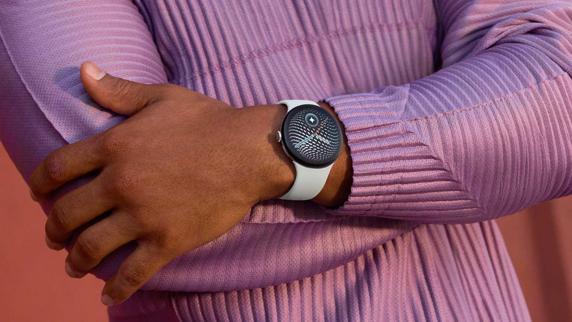 El Pixel Watch 5 con correa blanca en la muñeca de una persona con sweater lila