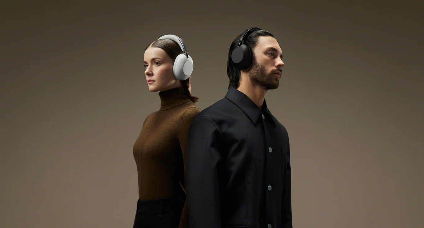 Male and female models wearing Sony 1000X The Collexion headphones in Platinum and Black colors against a light brown background