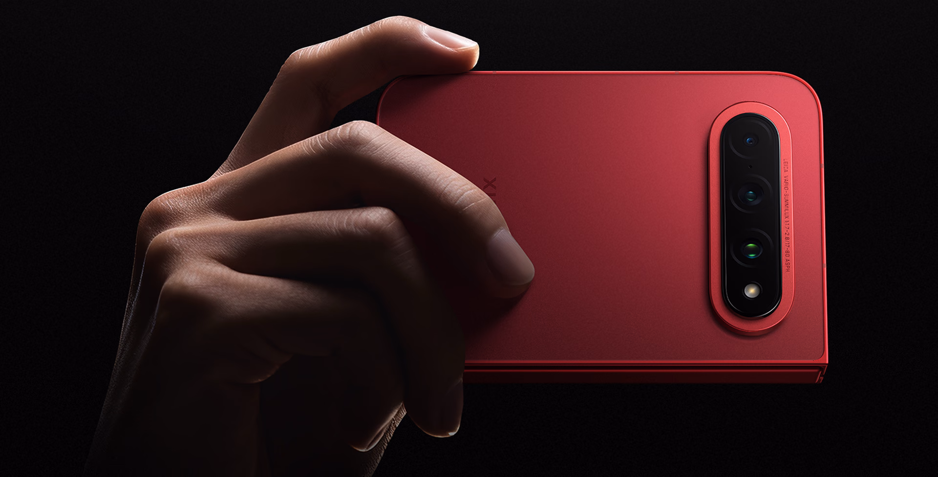 The red Xiaomi 18 Fold closed and held with two fingers against a black background
